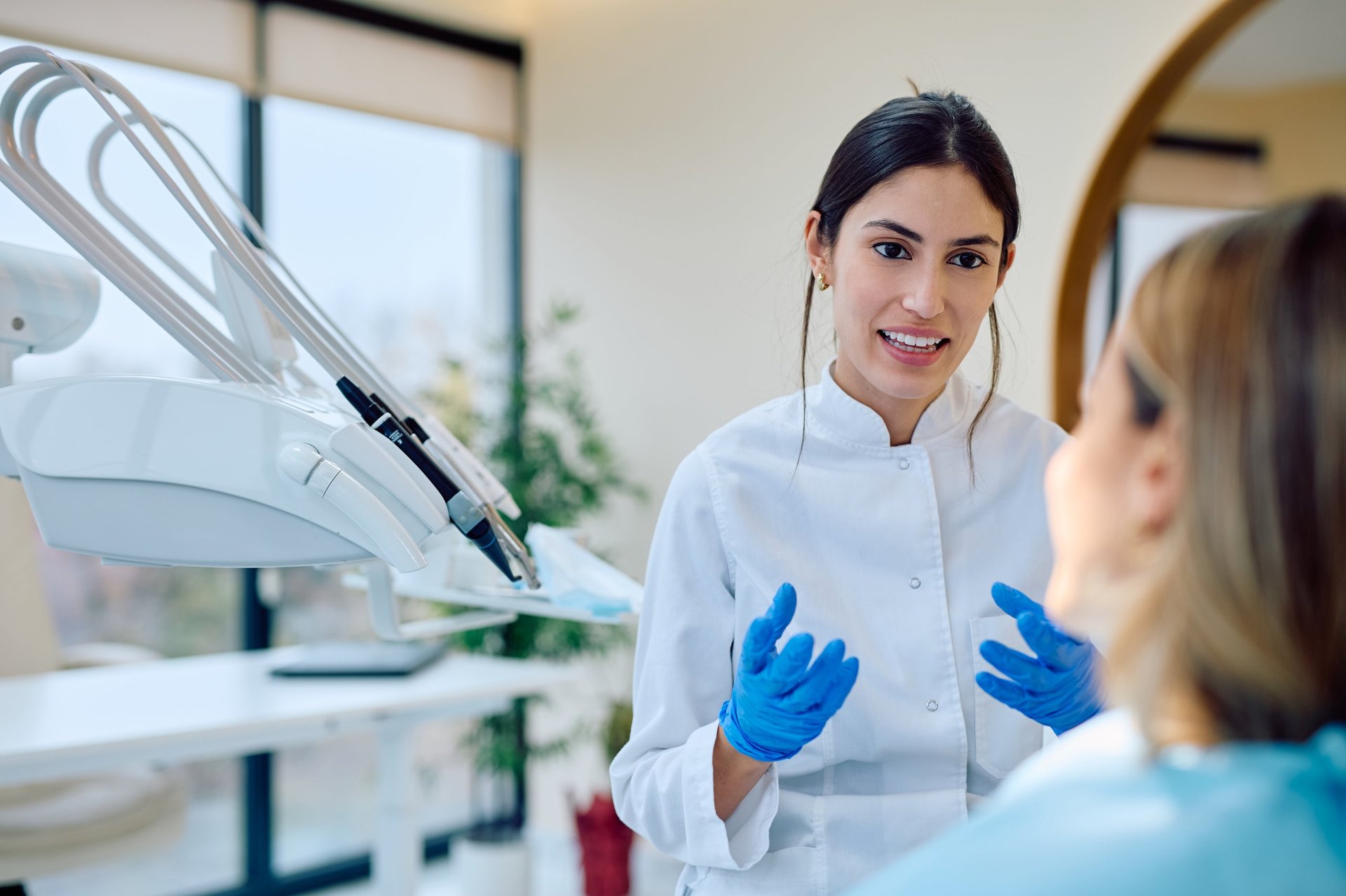 Young woman dentist consulting patient about oral health in a modern dental office, advising on checkup and hygiene