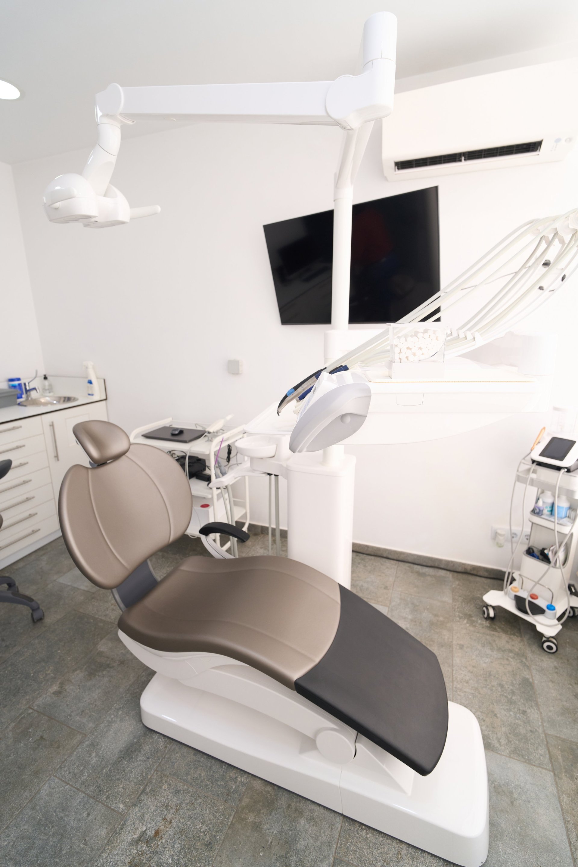 Empty modern dental clinic interior featuring a professional chair, adjustable lamp, and various medical instruments, emphasizing healthcare and hygiene